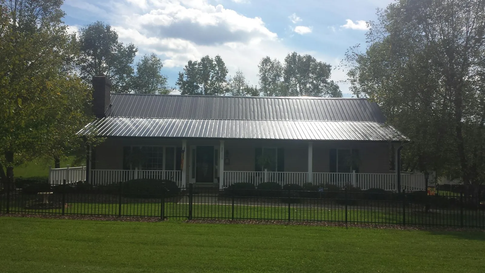 Gray metal roof on a brick ranch with a full width front porch — Gutter Guard Installation work by our crew in Norwich